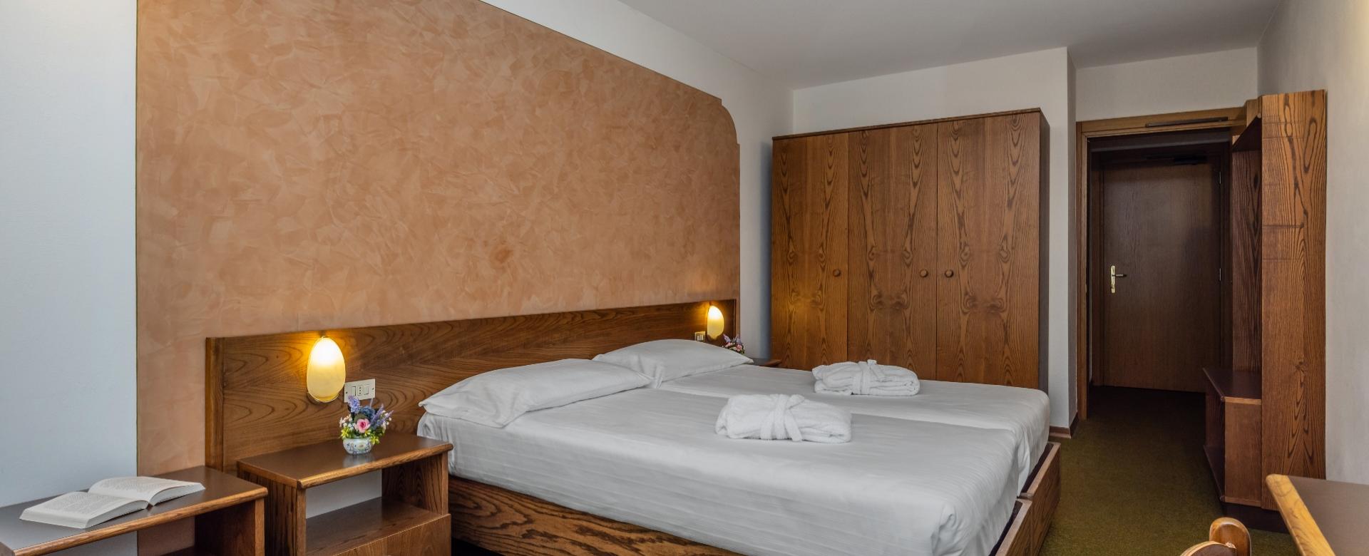 Gemütliches Hotelzimmer mit Doppelbett, Kleiderschrank und warmem Licht.