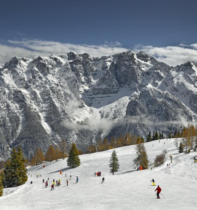 Skifahrer auf verschneiten Pisten mit majestätischen Bergen im Hintergrund.