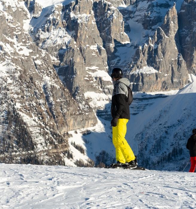 Skifahrer mit gelber Hose in verschneiten Bergen.