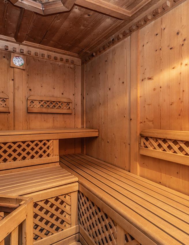 Sauna in legno con panche e termometro a parete.