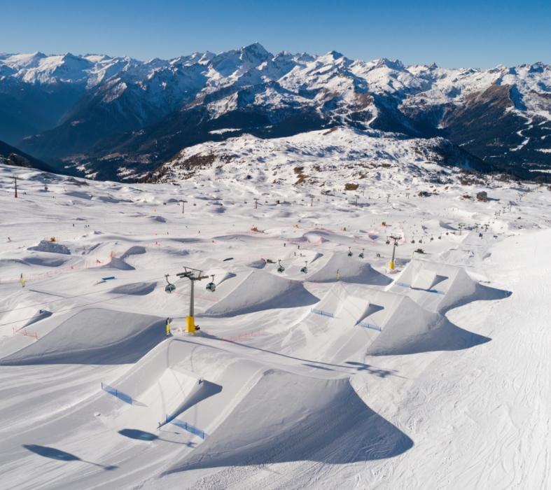 Panoramic view of a ski resort with snowy mountains and ski lifts.